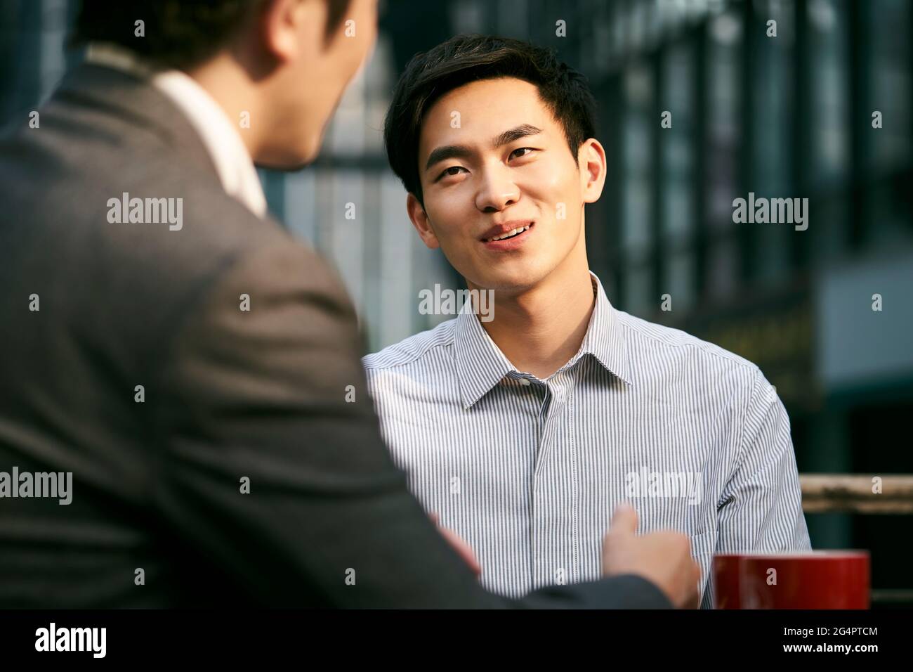 deux hommes d'affaires asiatiques discutent d'affaires lors d'un café en plein air boutique Banque D'Images