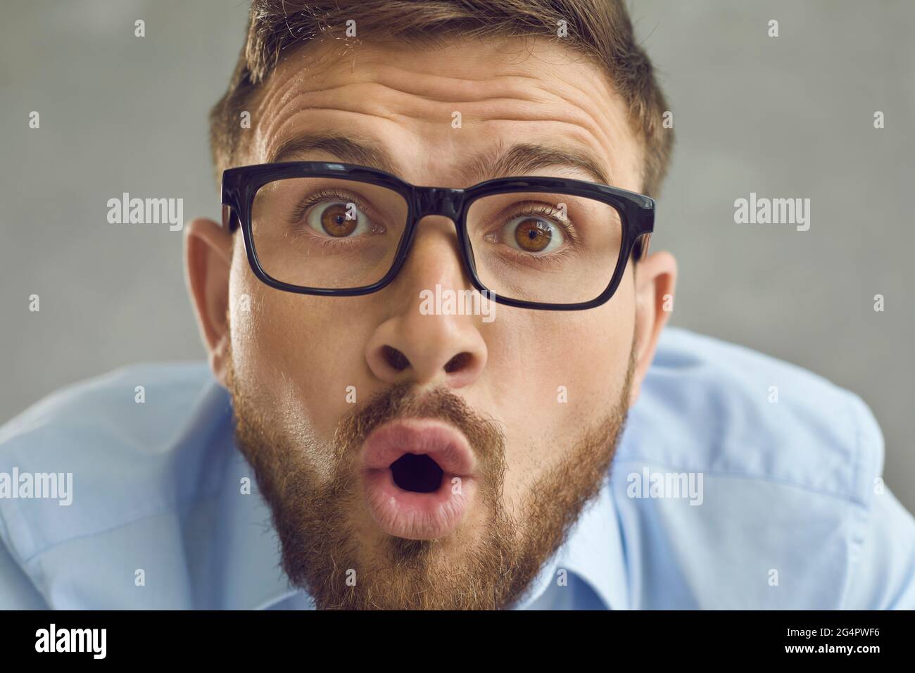 Gros plan choqué visage masculin drôle portrait studio tourné sur fond gris Banque D'Images