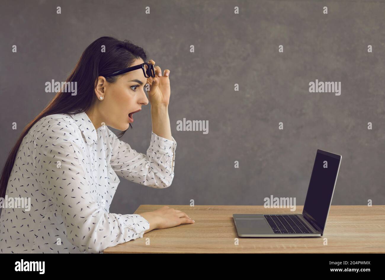 Vue latérale d'une jeune femme avec une expression choquée regardant un écran d'ordinateur portable. Banque D'Images