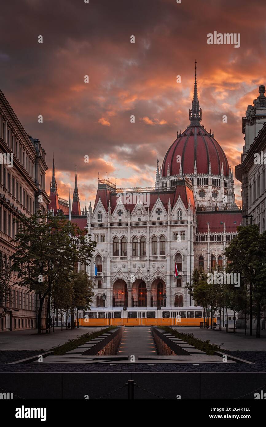 Budapest, Hongrie - le Mémorial de l'unité nationale et le Parlement de Hongrie avec le tram jaune traditionnel et le magnifique coucher de soleil coloré ciel et les nuages Banque D'Images