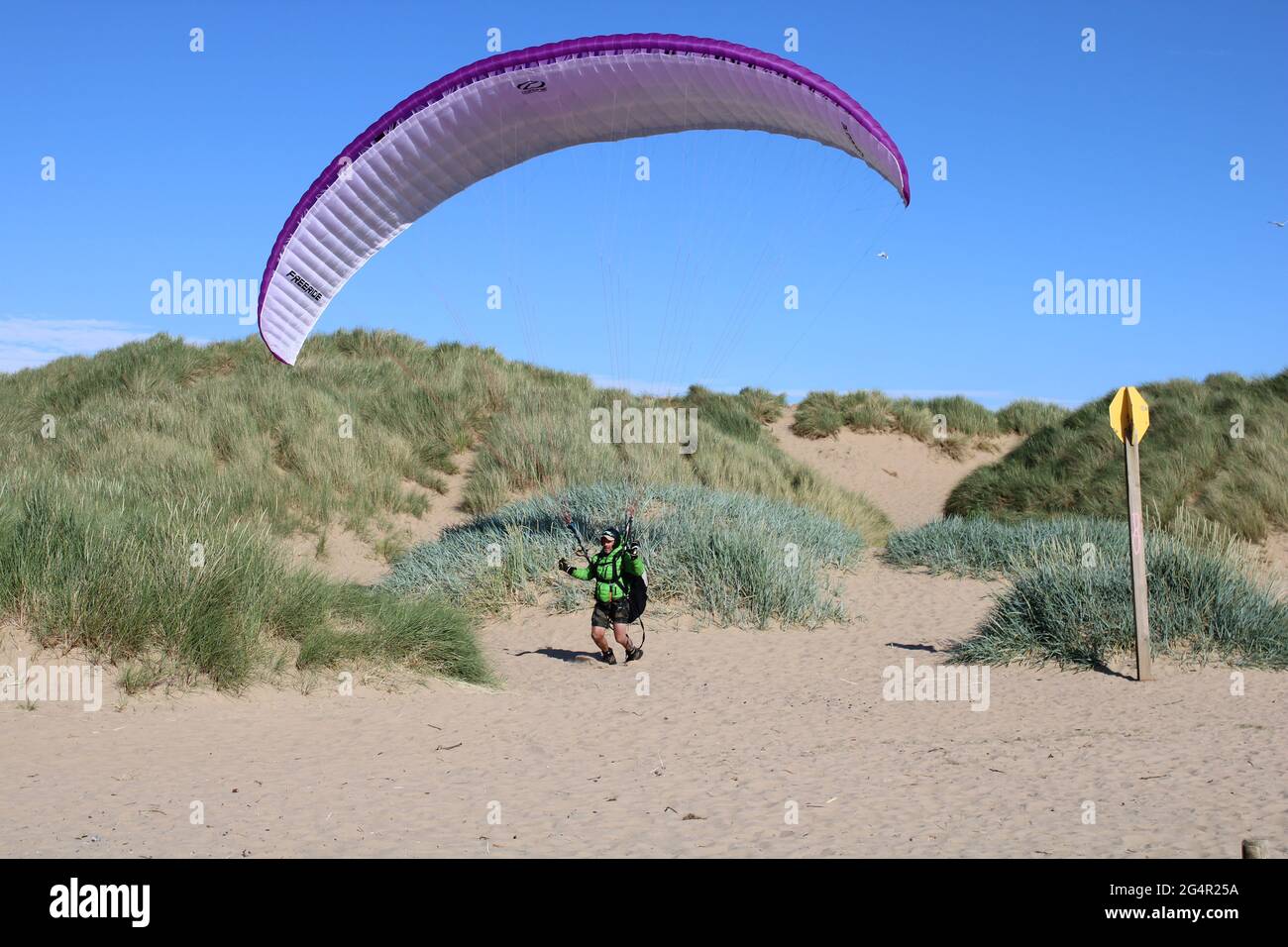 Vue sur la plage et les dunes de sable avec le concept de parapente mâle senior dans la distance, senior actif Banque D'Images