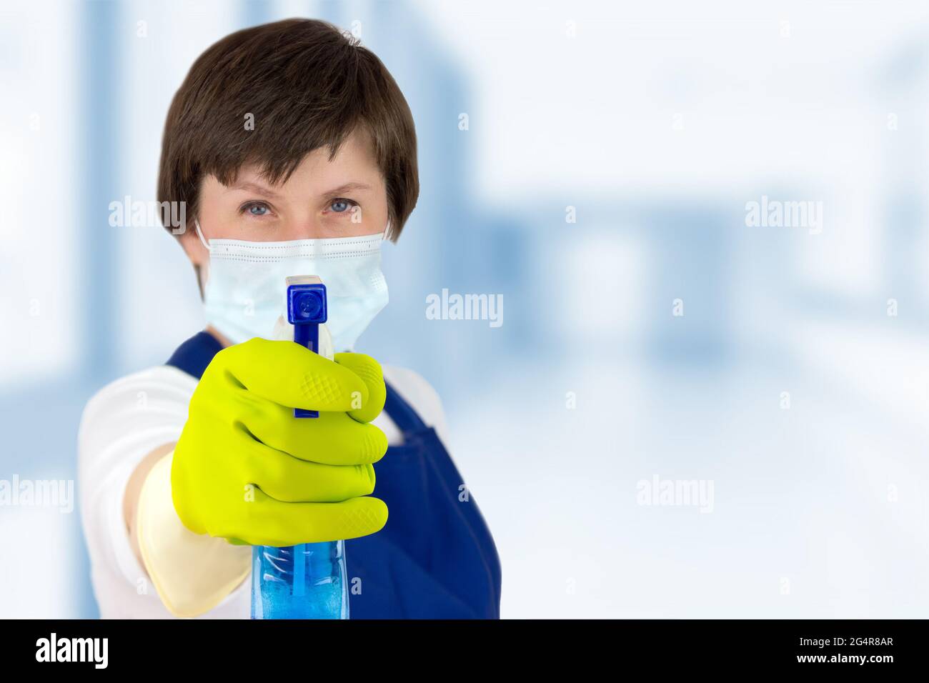 Femme de service de nettoyage tenant des vaporisateurs pour la surface de fenêtre en verre la dirigeant vers la caméra. Femme en uniforme et gants en caoutchouc tenant le spray nettoyant wi Banque D'Images