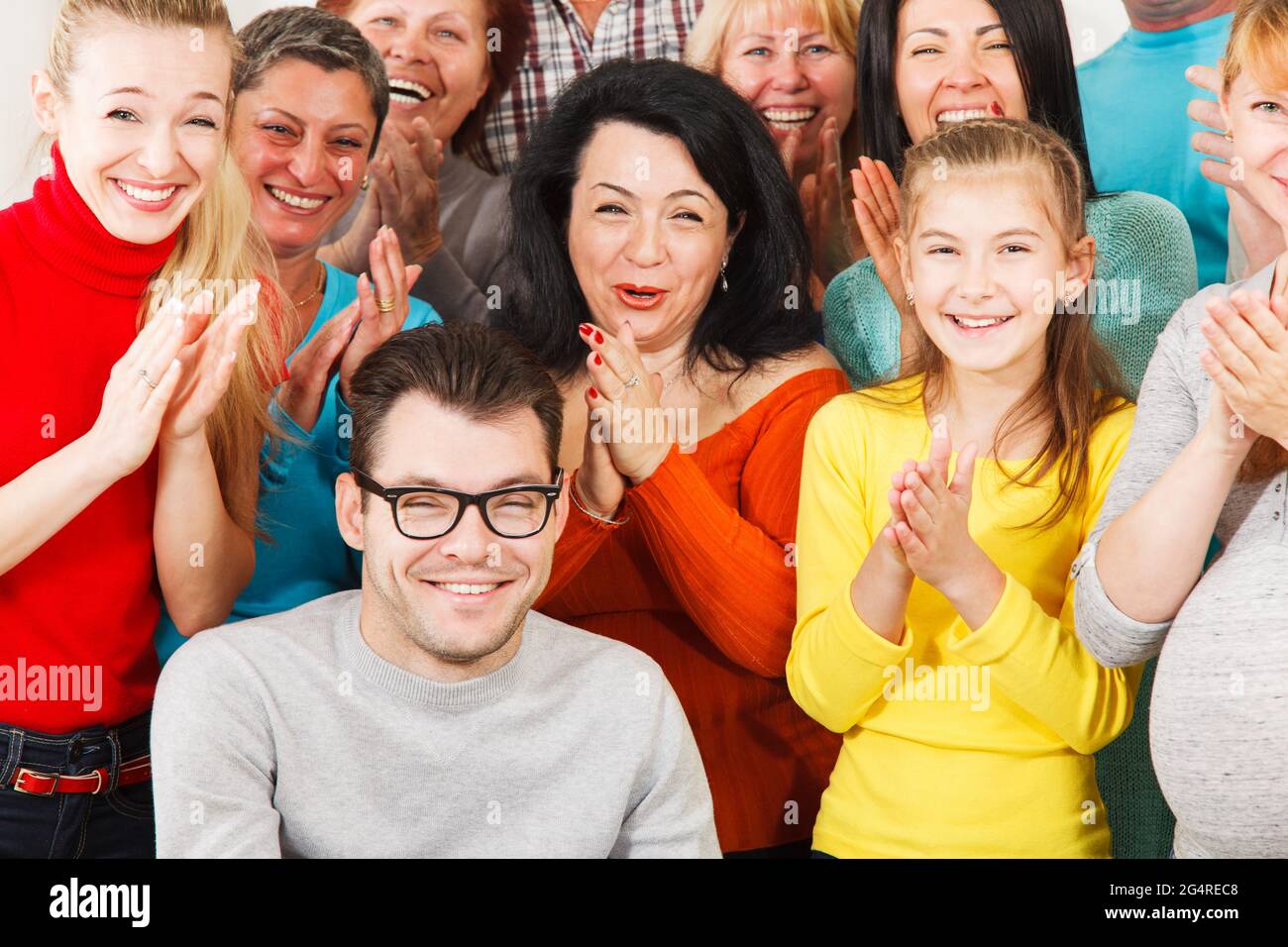 Un grand groupe de gens heureux souriant et claquant leurs mains. Banque D'Images