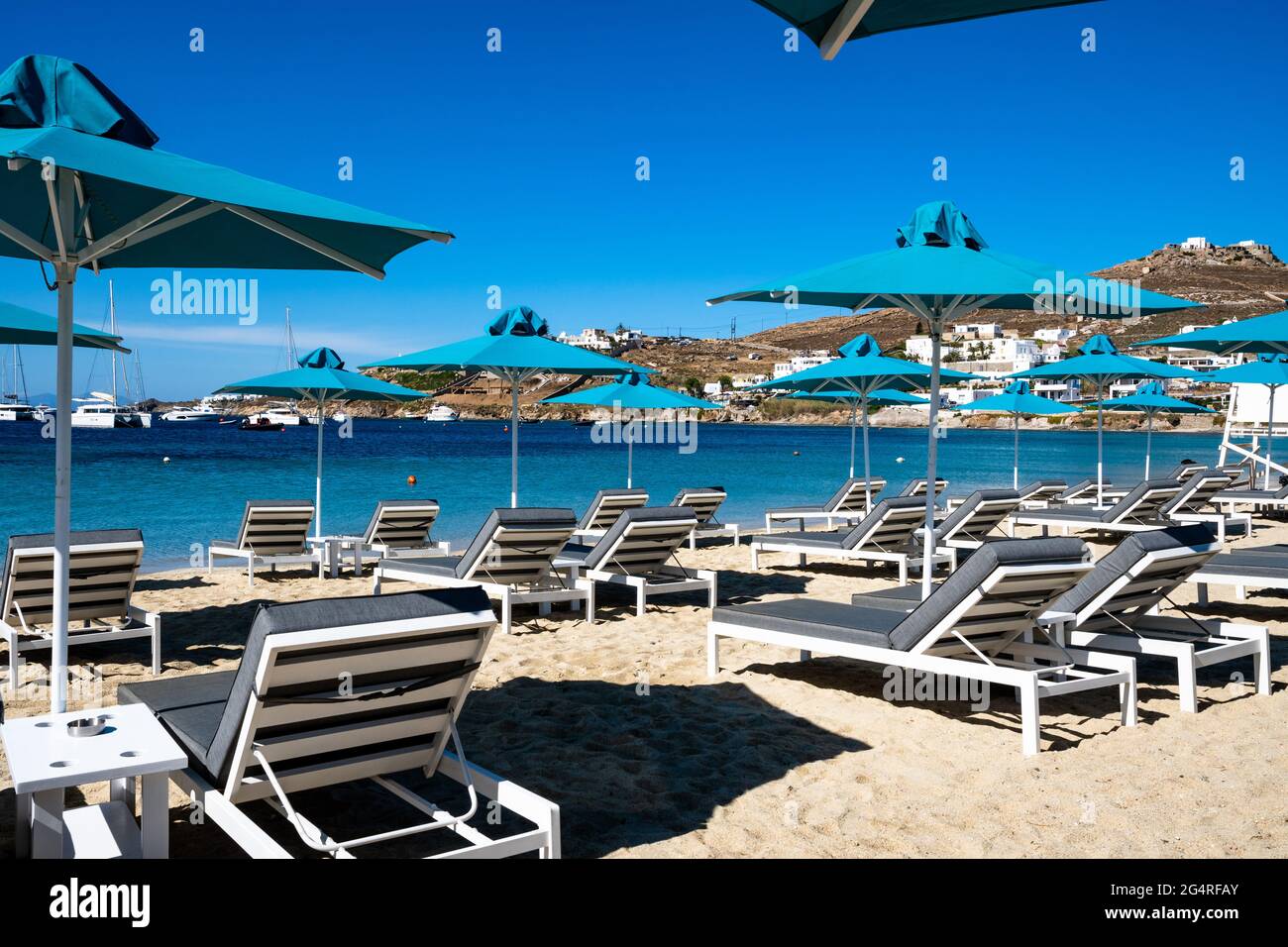 Parasols de plage et chaises longues à Ornos. Mykonos, Grèce. Banque D'Images