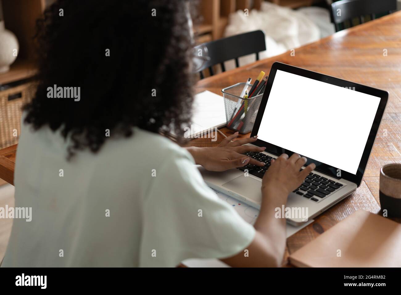 Une femme est assise devant un ordinateur portable ouvert et un smartphone avec un écran vide vierge pour vos informations ou votre contenu Banque D'Images