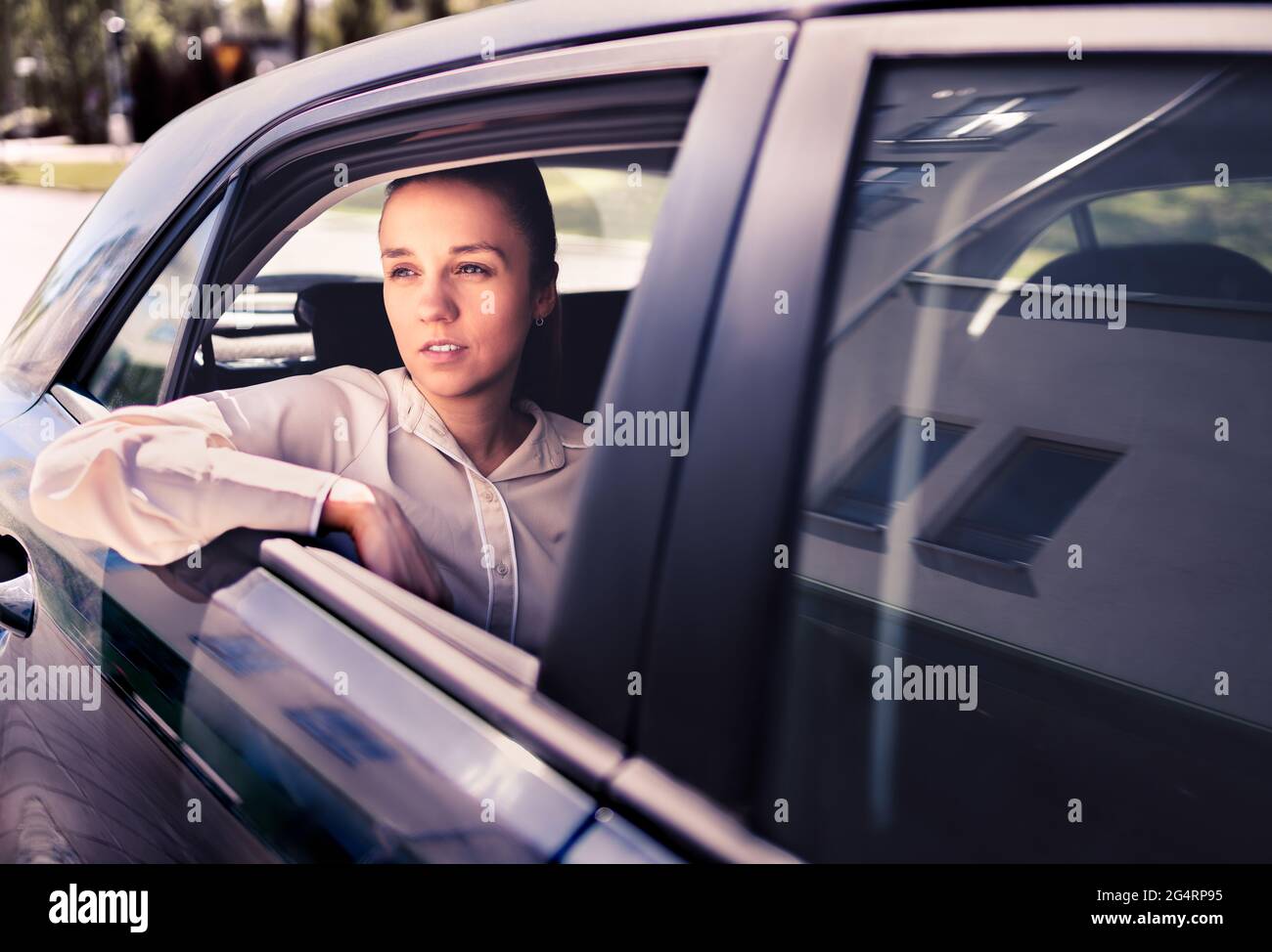 Femme sérieuse en voiture. Un taxi triste, contrarié ou fatigué. Cool et élégante femme d'affaires assise sur la banquette arrière donnant sur la fenêtre. Banque D'Images