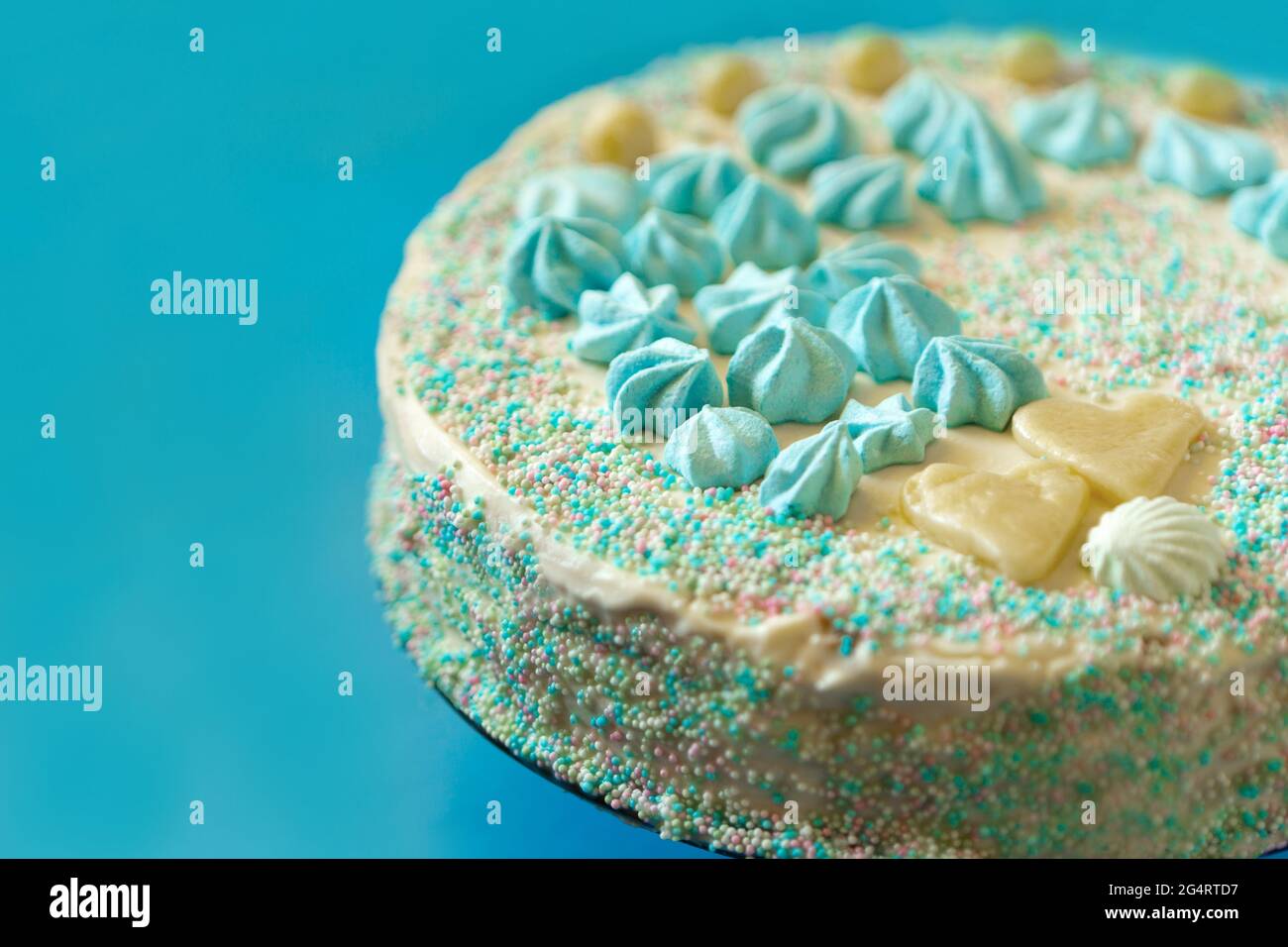 gâteau bleu avec bonbons pour la fête de la douche de bébé avec vue rapprochée sur la meringue. Gâteau fait maison pour un nouveau-né sur fond bleu. Banque D'Images