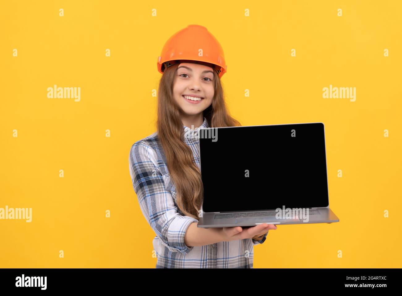 jeune fille dans le casque présentant ordinateur portable. ordinateur de garde d'enfant de constructeur. bâtiment et construction. Banque D'Images