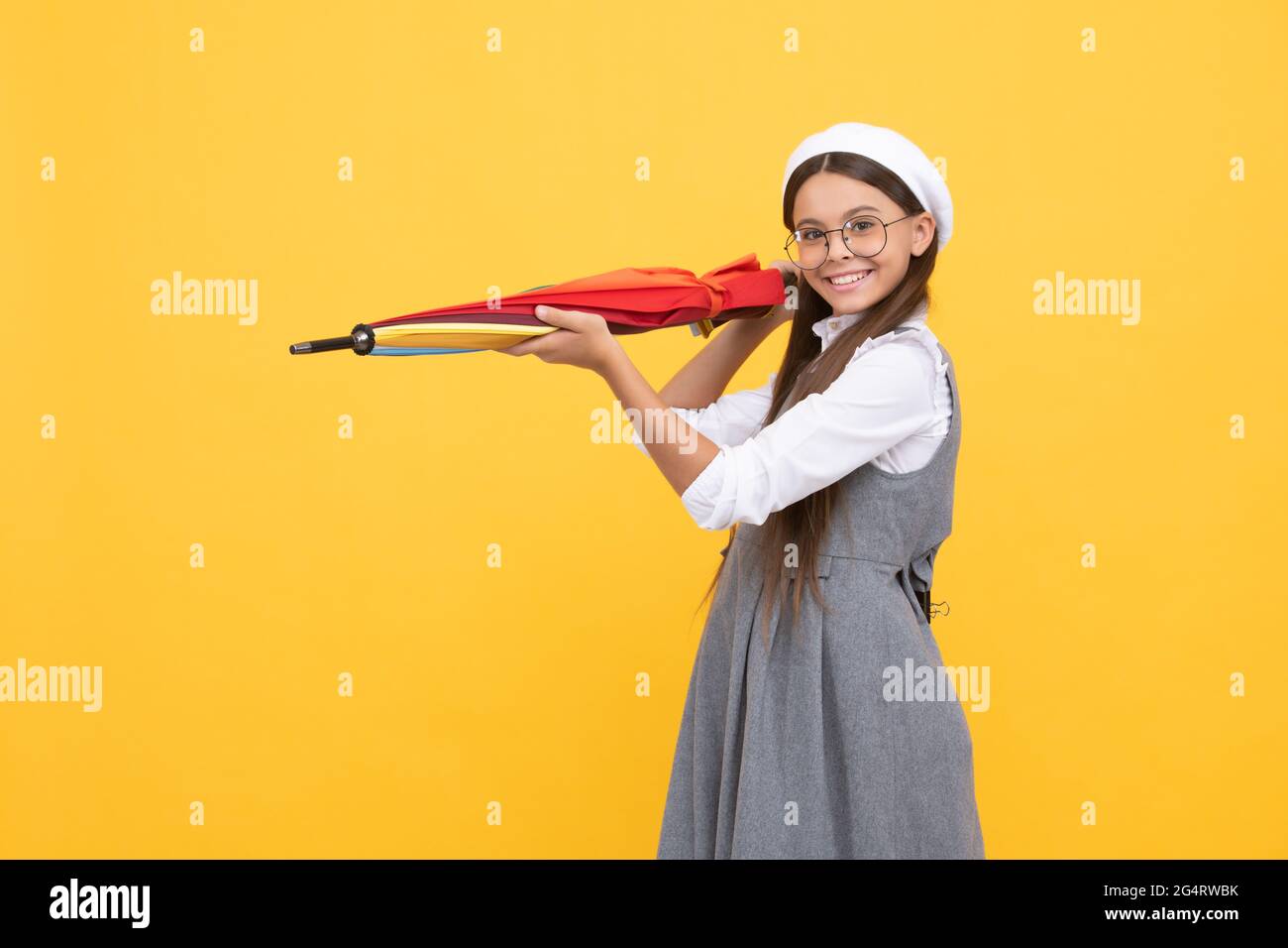 bonne adolescente en lunettes et beret tenir un parapluie coloré pour la protection contre la pluie, les prévisions météorologiques. Banque D'Images