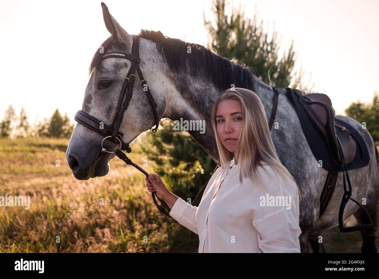 jeune femme blonde marchant avec son cheval Banque D'Images