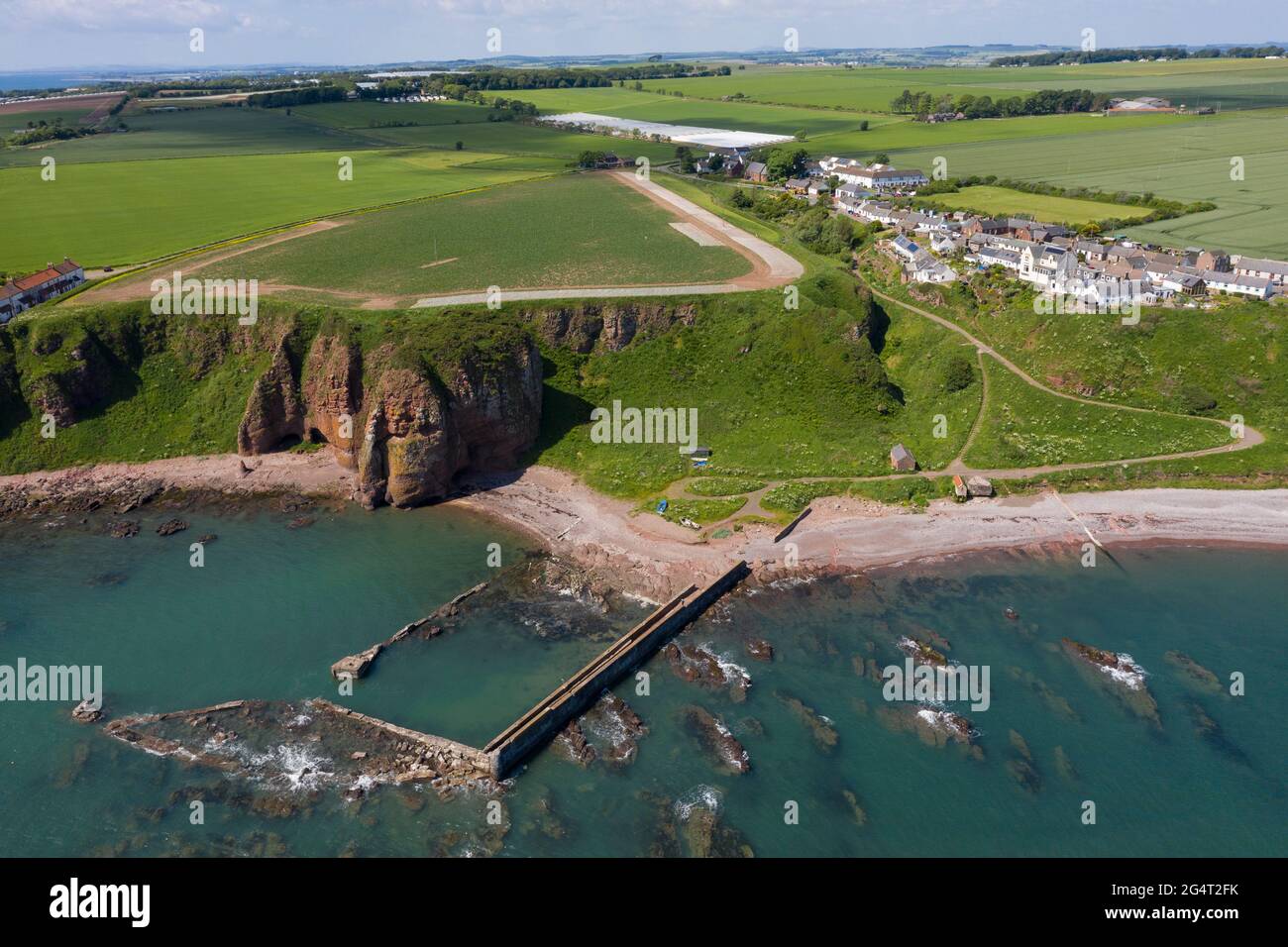 Vue aérienne du village d'Auchmithie, au sommet d'une falaise, et de sa plage et de son vieux port. Auchmithie a été l'endroit où le Smokie d'Arbroath a été produit pour la première fois. Banque D'Images