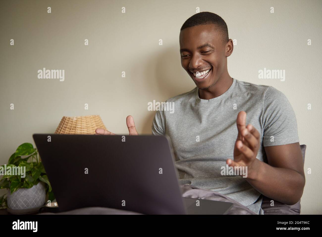 Rire un jeune Africain utilisant un ordinateur portable dans le lit à la maison Banque D'Images