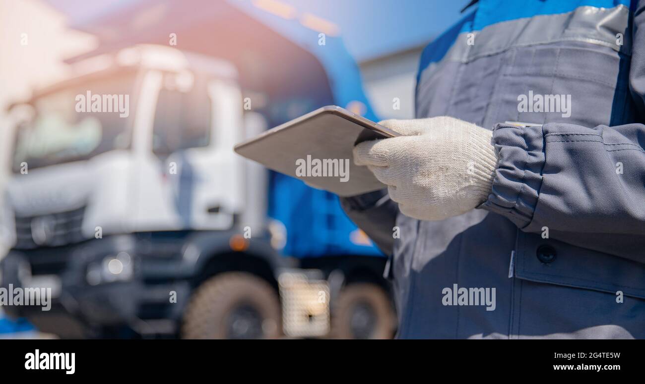 Concept bannière logistique automatisée en ligne Internet. Vider le conducteur de camion homme en uniforme avec ordinateur tablette commande le chargement de la cargaison ou du charbon. Banque D'Images