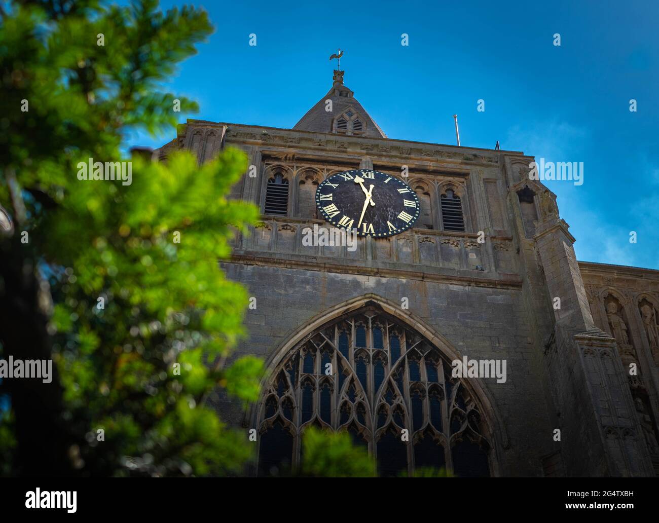 Gros plan de la tour de l'horloge, l'abbaye de Crowland, Lincolnshire, Royaume-Uni avec un arbre au premier plan pris lors d'une chaude journée d'été vers le milieu de la journée. Banque D'Images