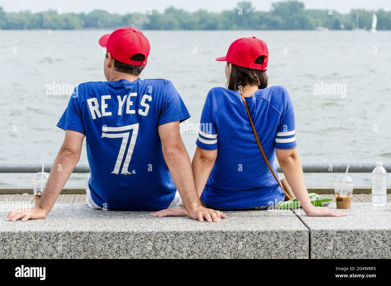 Un jeune couple qui profite des célébrations de la fête du Canada dans le secteur riverain de Toronto portant des uniformes Blue Jays. Banque D'Images