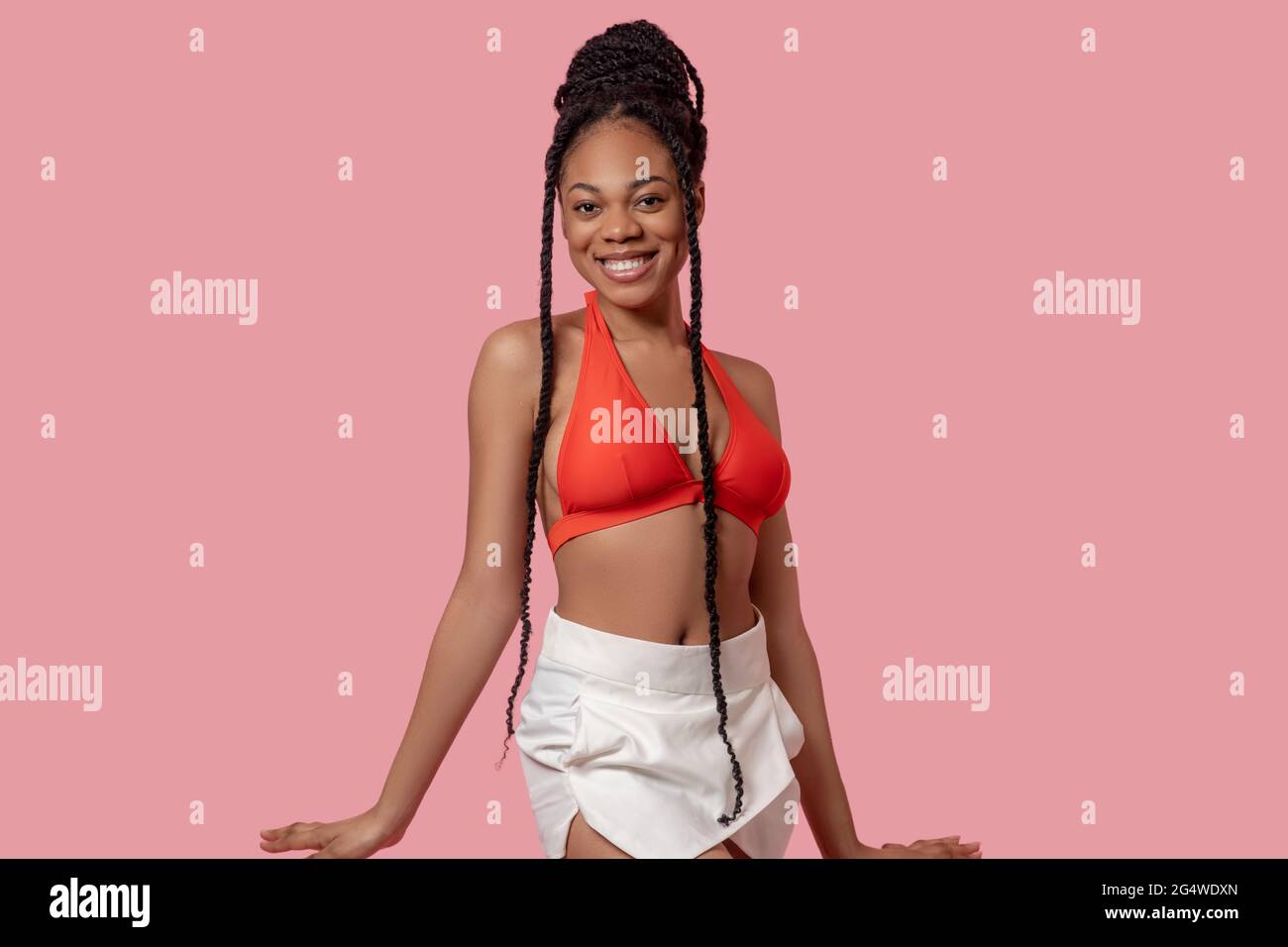 Jolie femme afro-américaine en haut orange qui a l'air joyeuse Banque D'Images