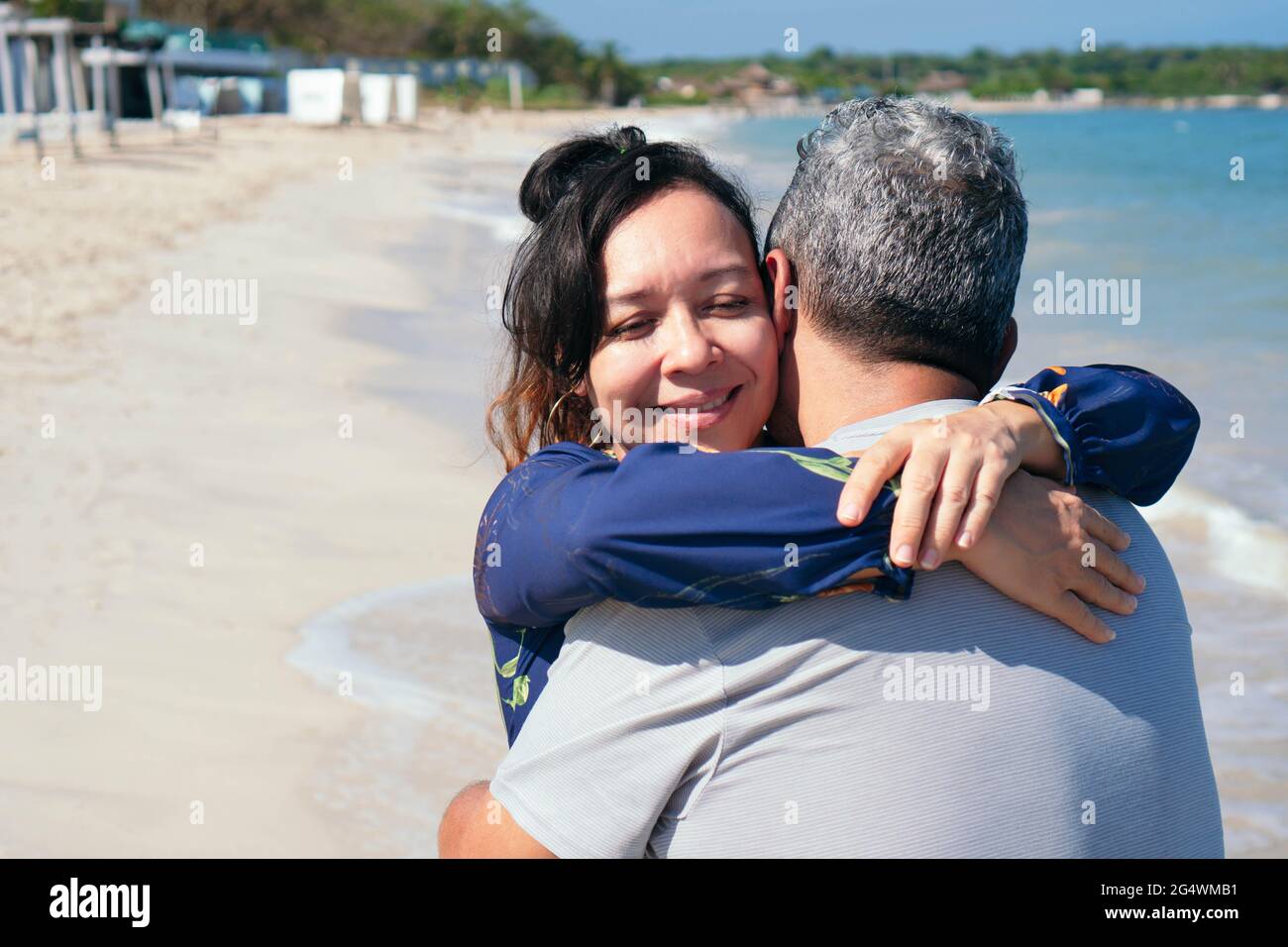 Couple hispanique d'âge moyen qui s'embrasse sur une plage. Banque D'Images