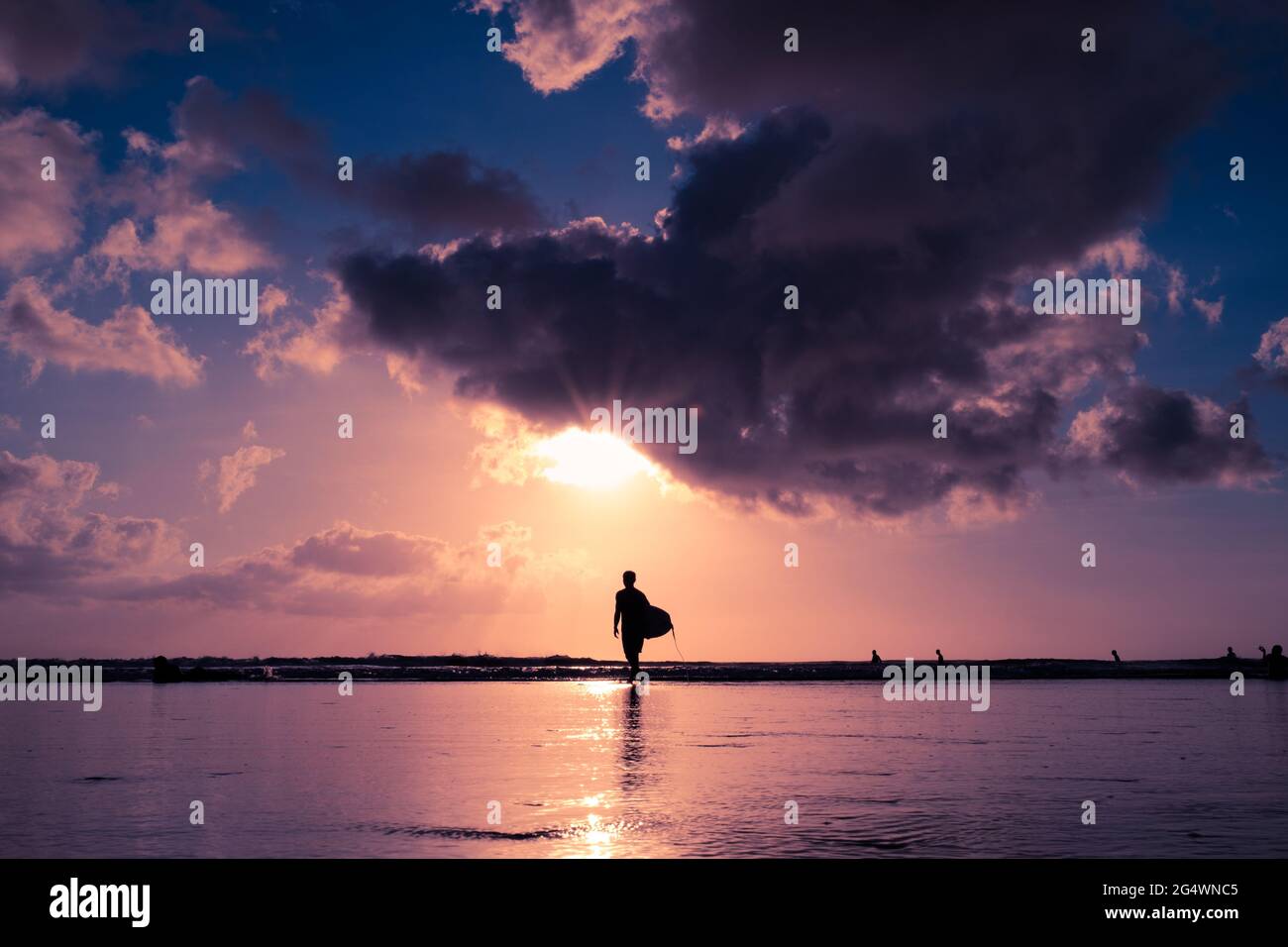 Surfer de Bali hors de l'eau avant le coucher du soleil à Kuta Beach Banque D'Images