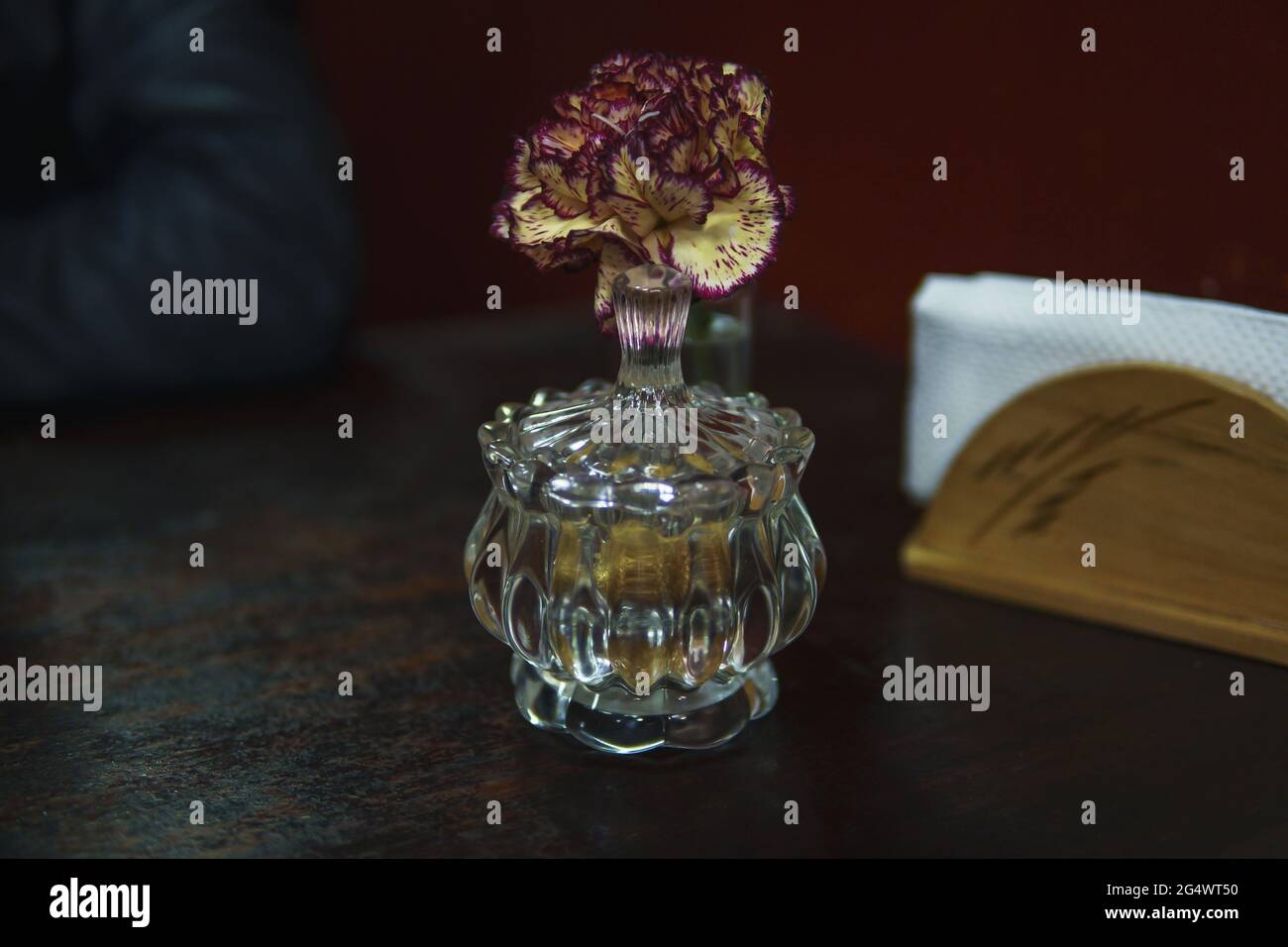 Mini vase en verre avec une carnation pourpre sur la table du dîner Banque D'Images
