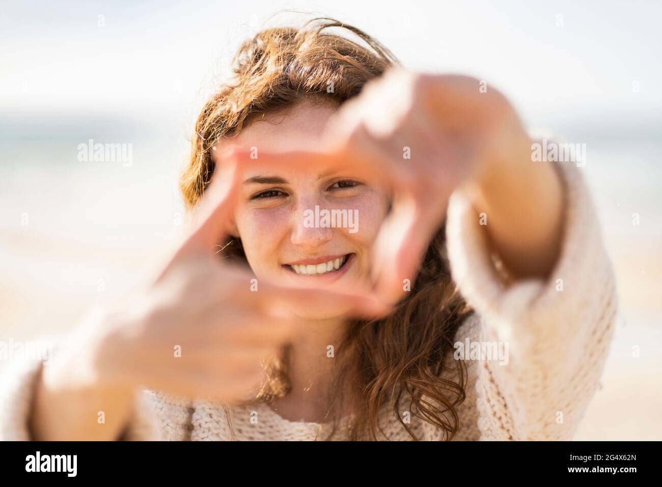 Femme souriante faisant le doigt à la plage pendant les vacances Banque D'Images