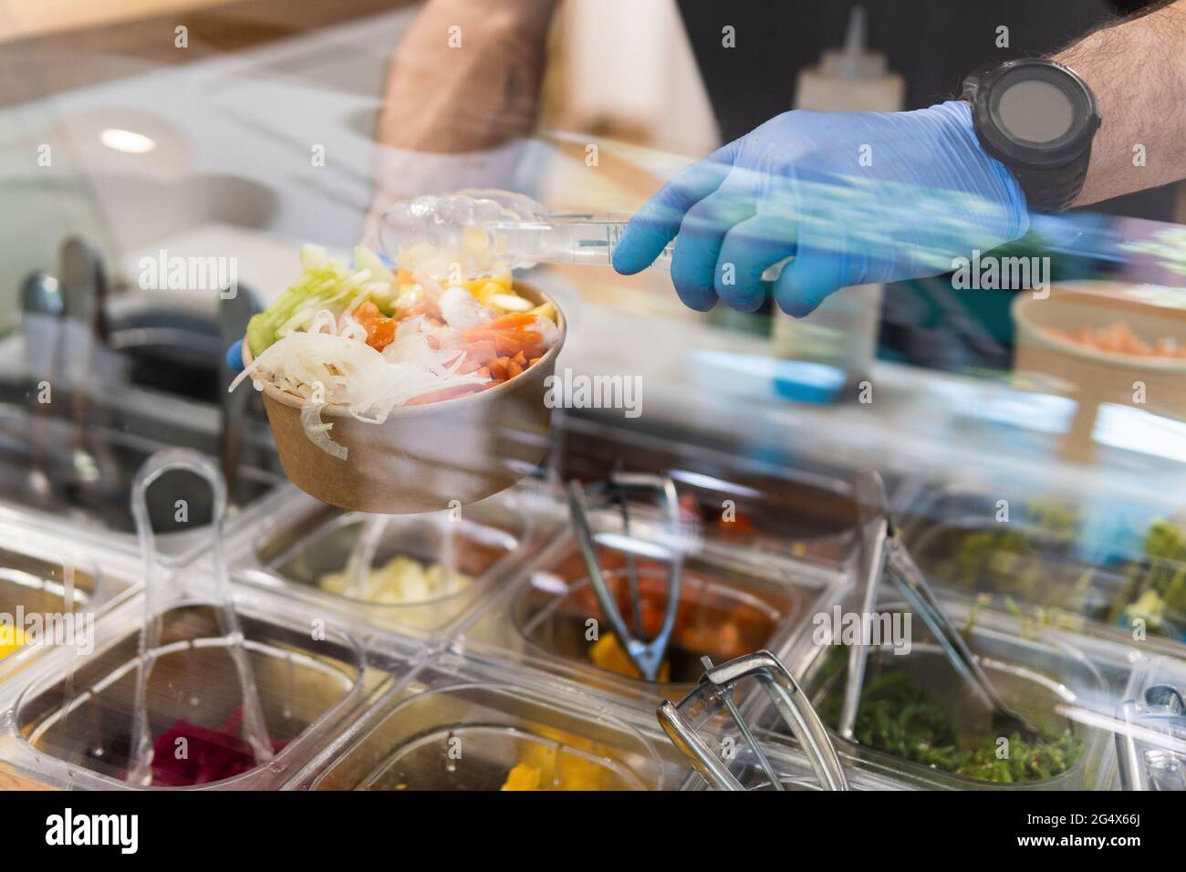 Chef avec des gants de protection pour préparer la salade au bar du restaurant Banque D'Images