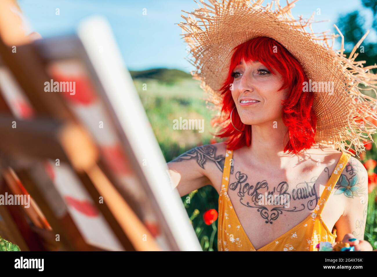 Femme souriante tatouée avec des cheveux rouges peint le jour ensoleillé Banque D'Images