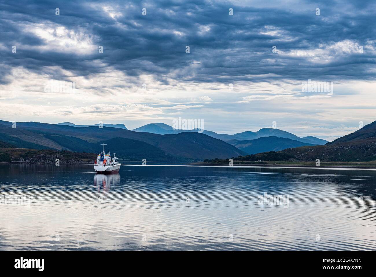 Royaume-Uni, Écosse, Ullapool, nuages sur un seul bateau de pêche naviguant dans la baie des Highlands écossais Banque D'Images