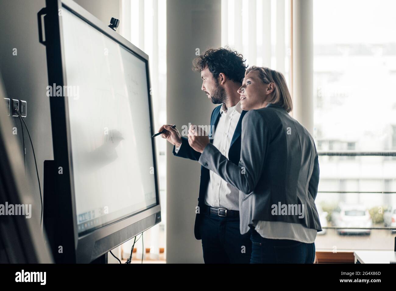 Équipe professionnelle travaillant sur écran de projection au bureau Banque D'Images