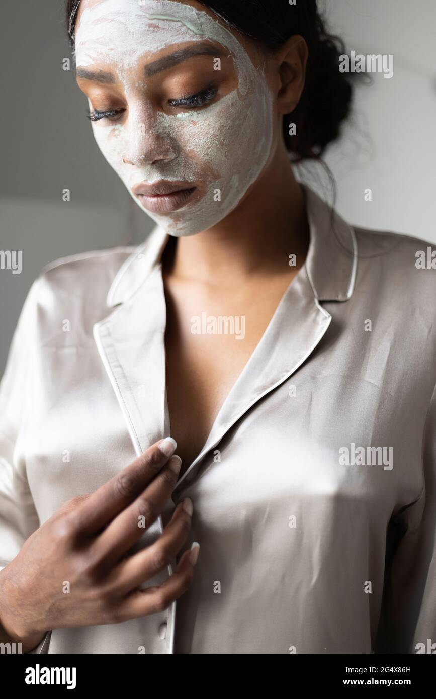 Femme réfléchie avec masque de beauté sur le visage Banque D'Images