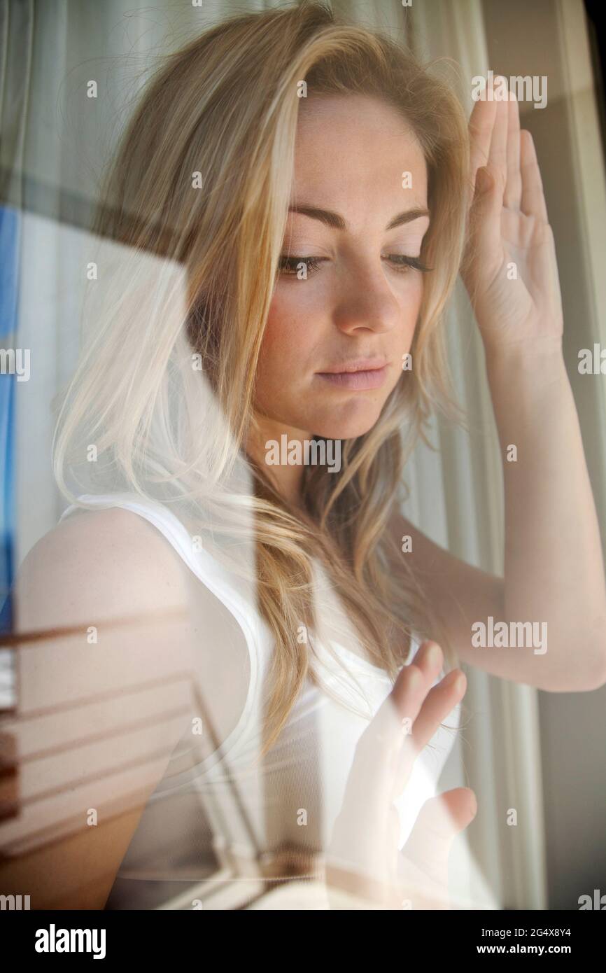 Jeune femme blonde vue à travers la vitre à la maison Banque D'Images