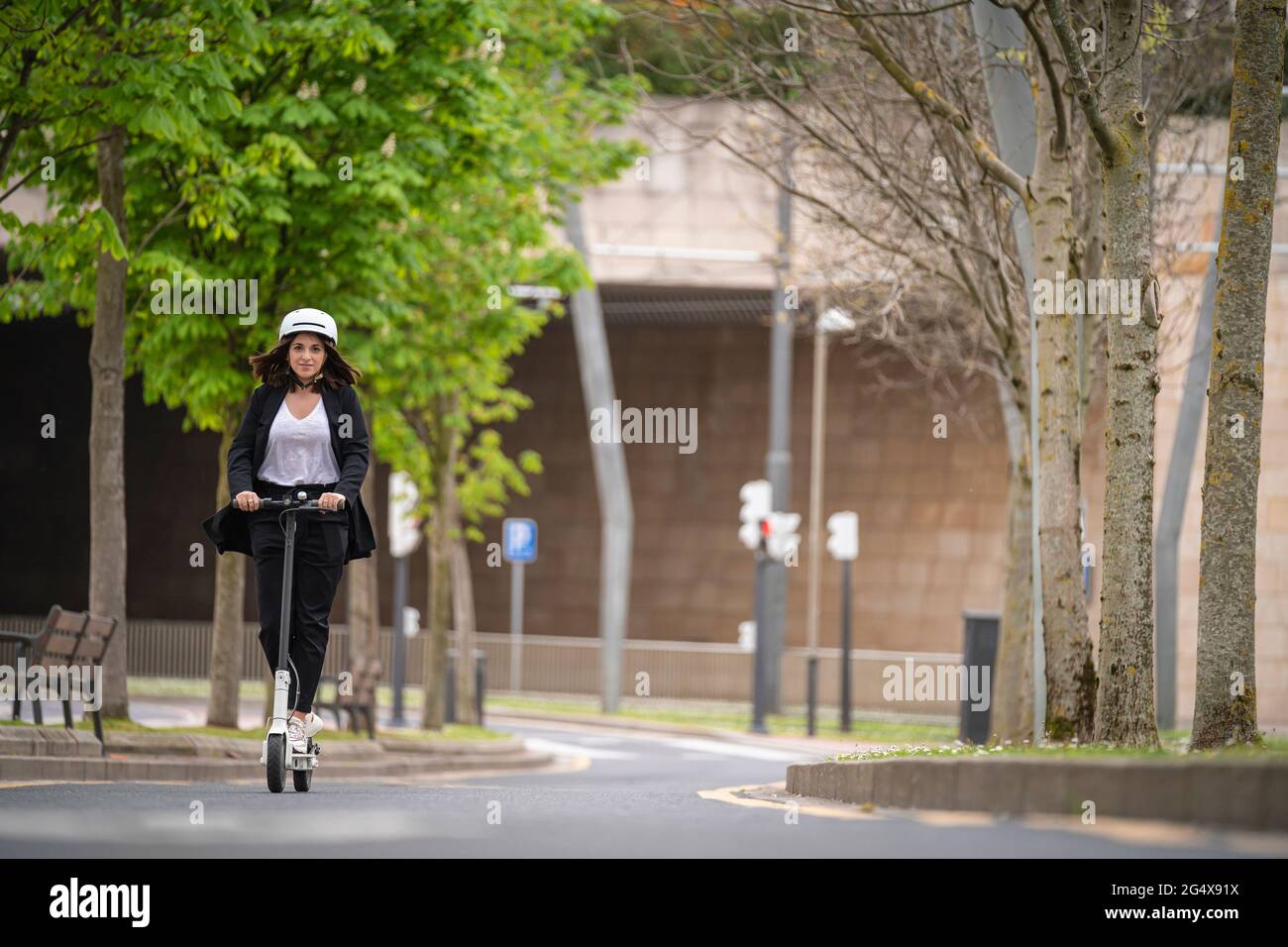Femme d'affaires à bord d'un scooter électrique sur route Banque D'Images