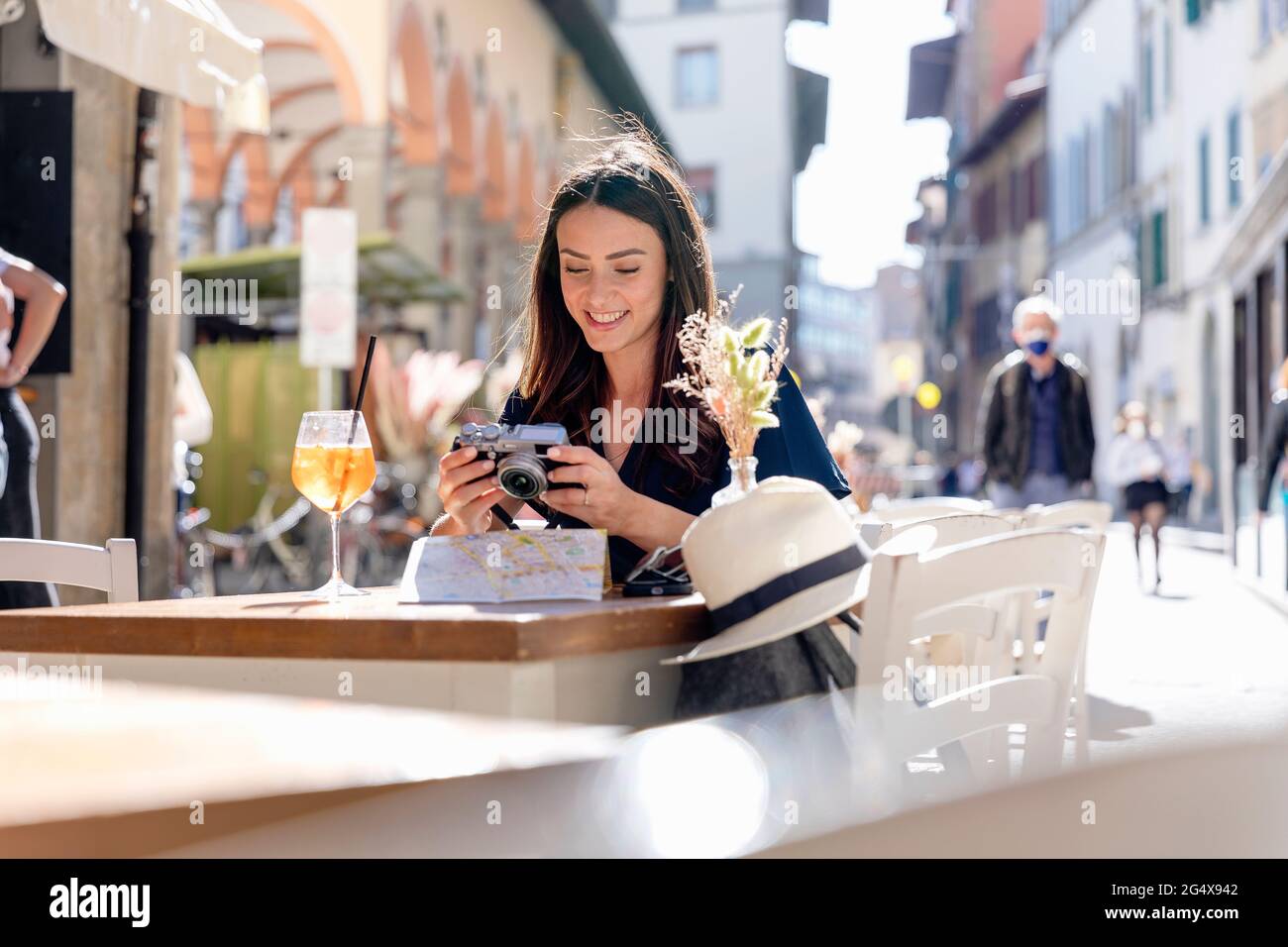 Femme souriante qui vérifie la caméra au café-terrasse Banque D'Images