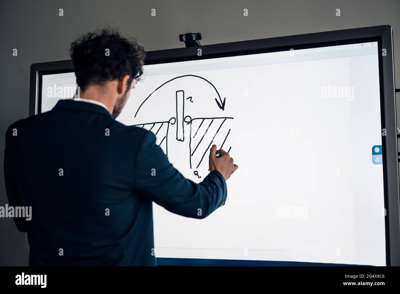 Homme d'affaires qui dessine sur un écran de projection tout en travaillant au bureau Banque D'Images