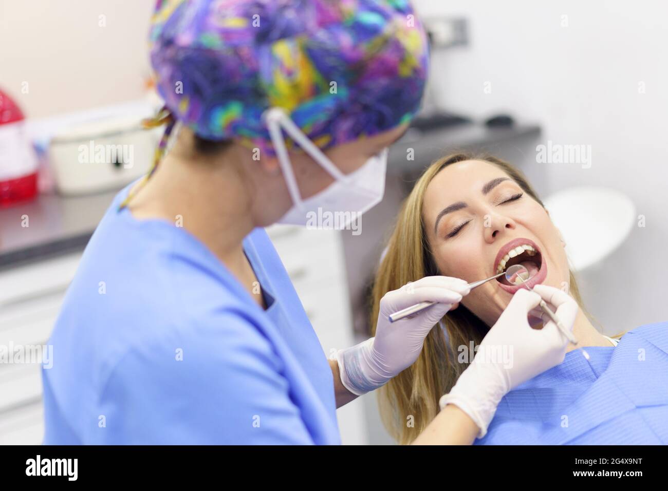 Une femme dentiste porte des gants chirurgicaux pour examiner les dents du patient dans une clinique médicale Banque D'Images