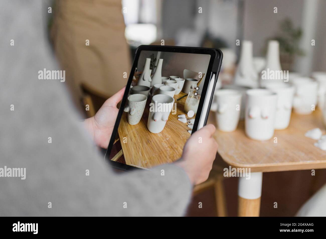 Artiste féminine photographiant des produits d'art à l'aide d'une tablette numérique lors d'un atelier Banque D'Images