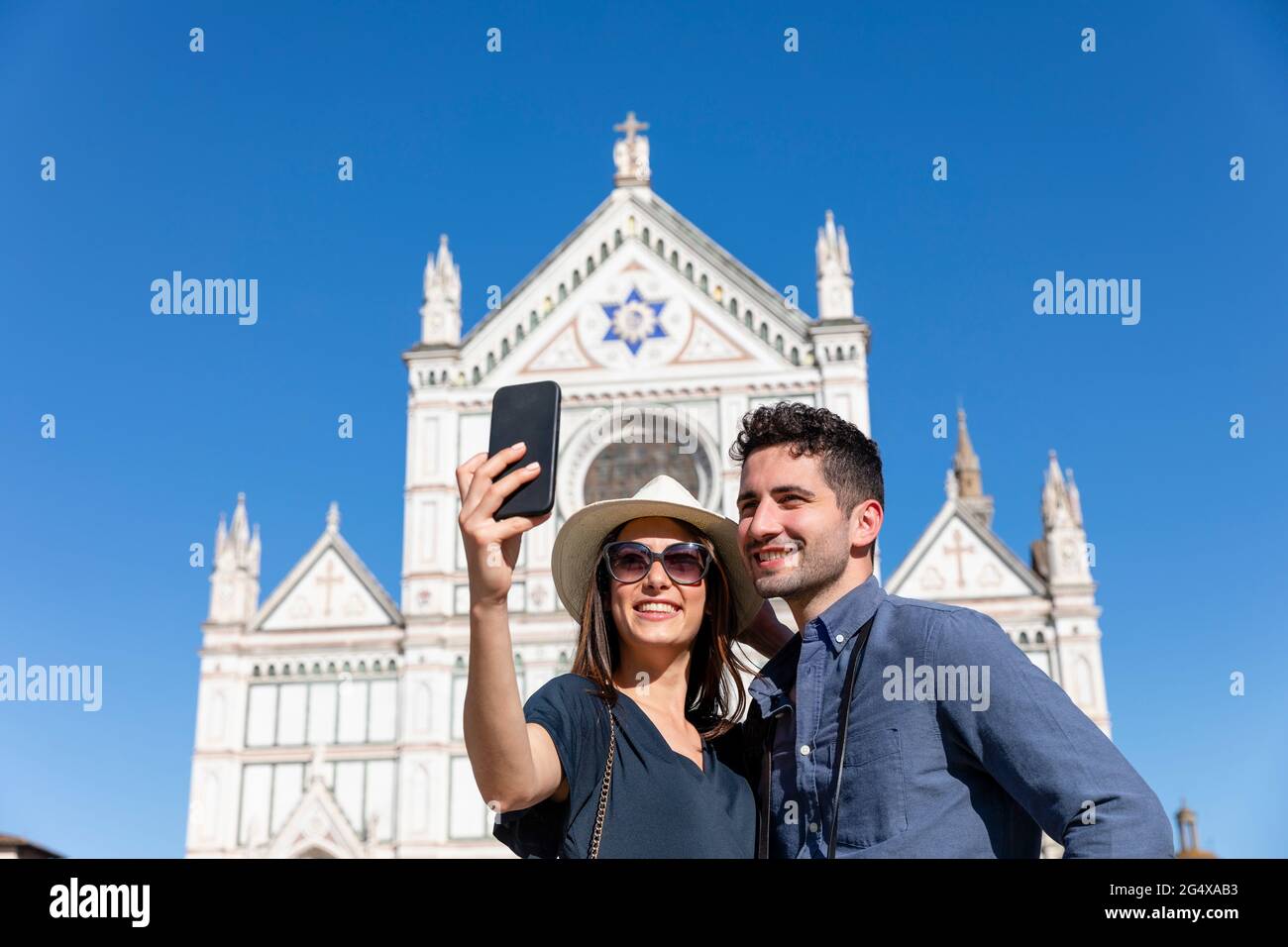 Couple de touristes prenant le selfie à travers le smartphone en face de la basilique de Santa Croce, Florence, Italie Banque D'Images