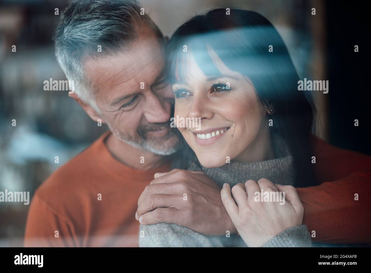 Homme mûr avec le bras autour de la femme souriant au café Banque D'Images