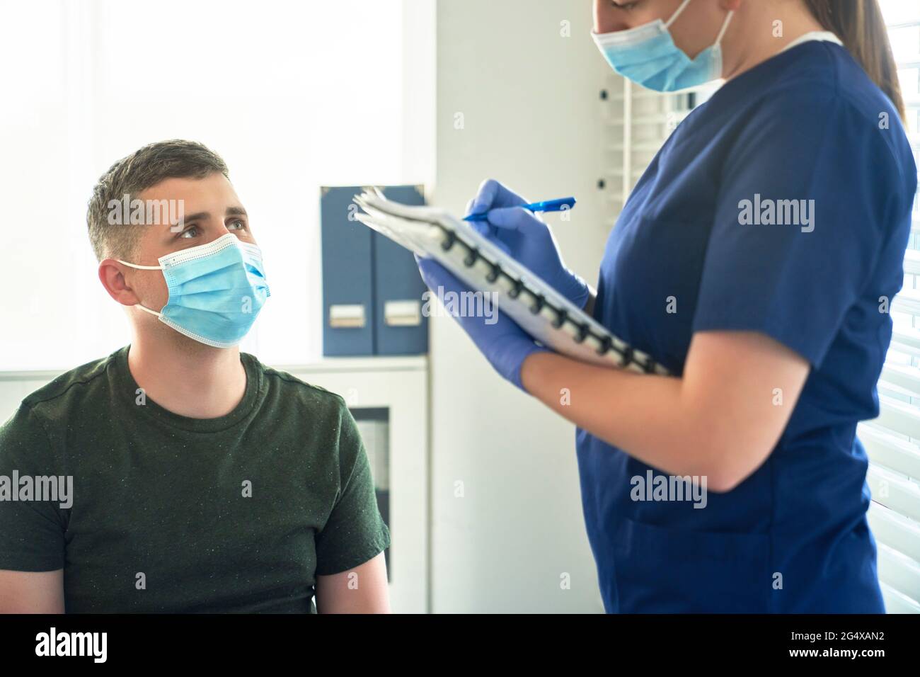 Femme médecin dans le masque facial de protection prenant l'entrevue du patient avant la vaccination à la clinique Banque D'Images