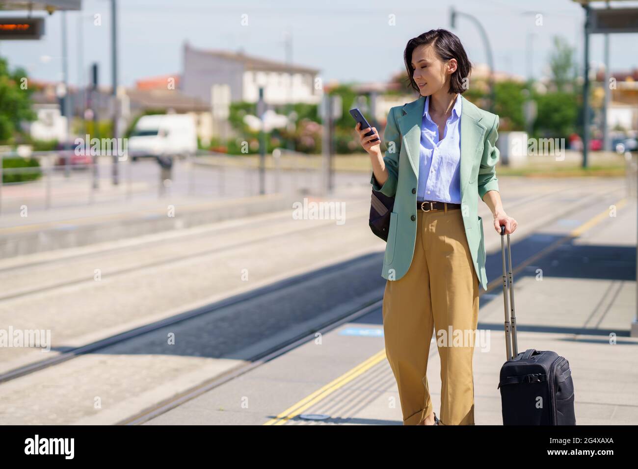 Femme professionnelle utilisant un smartphone en attendant le train à la gare Banque D'Images