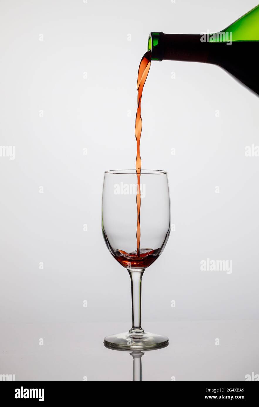 Verser le vin rouge dans un verre transparent. Banque D'Images