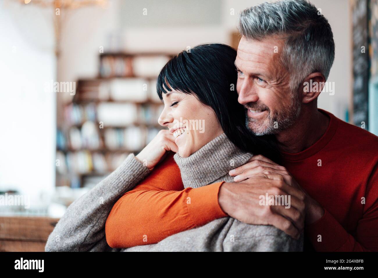 Homme souriant avec le bras autour sur une femme regardant loin dans le café Banque D'Images