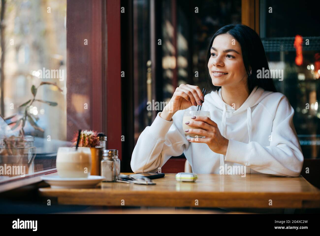 Femme attentionnés avec de la paille de boire du café au café Banque D'Images