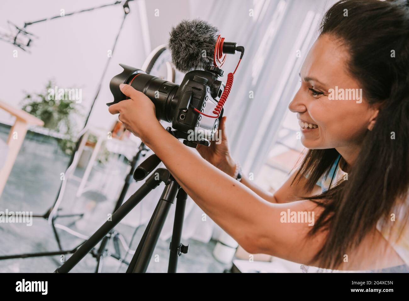 Femme souriante qui règle la caméra pendant qu'elle filme en studio Banque D'Images