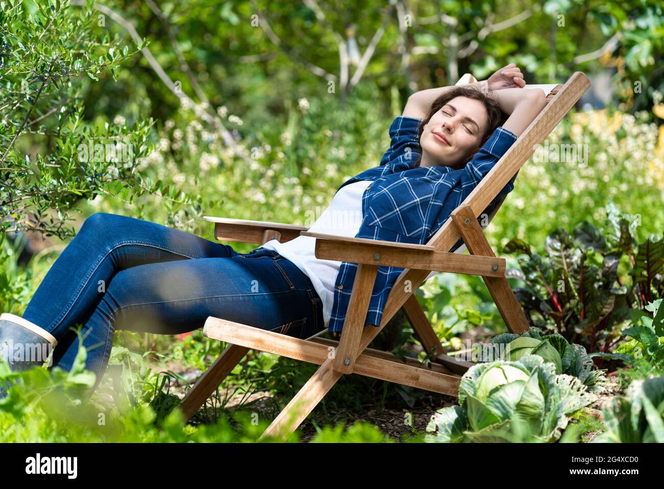 Jeune femme dormant sur une chaise dans un potager biologique Banque D'Images