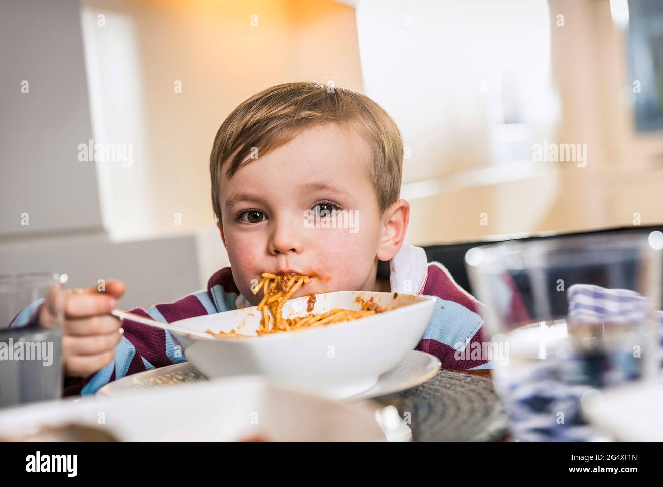 Un adorable garçon qui se fait regarder tout en mangeant de la nourriture à la maison Banque D'Images