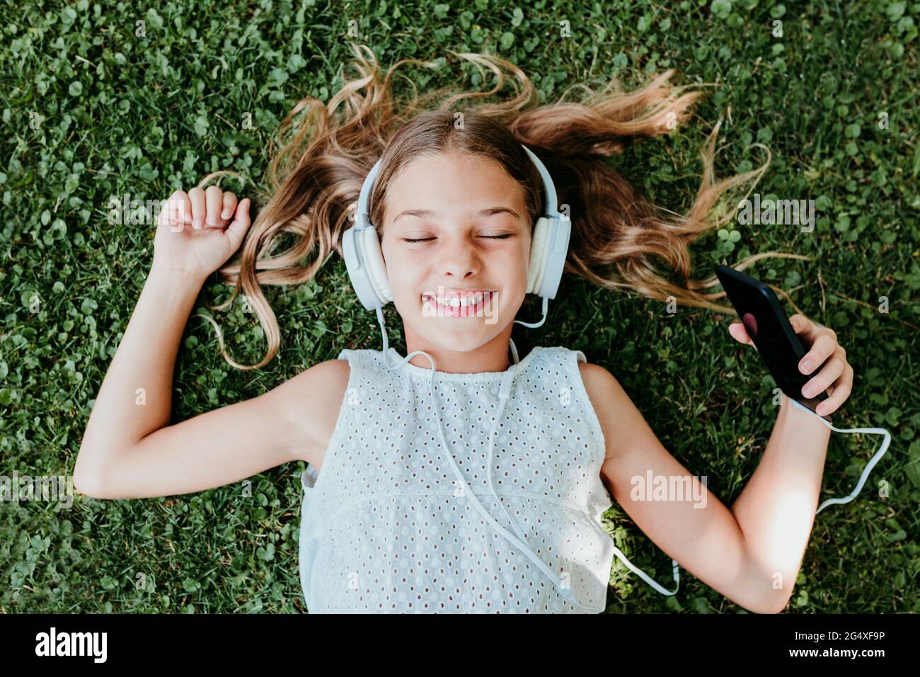 Fille souriante avec les yeux fermés couché sur l'herbe en été Banque D'Images