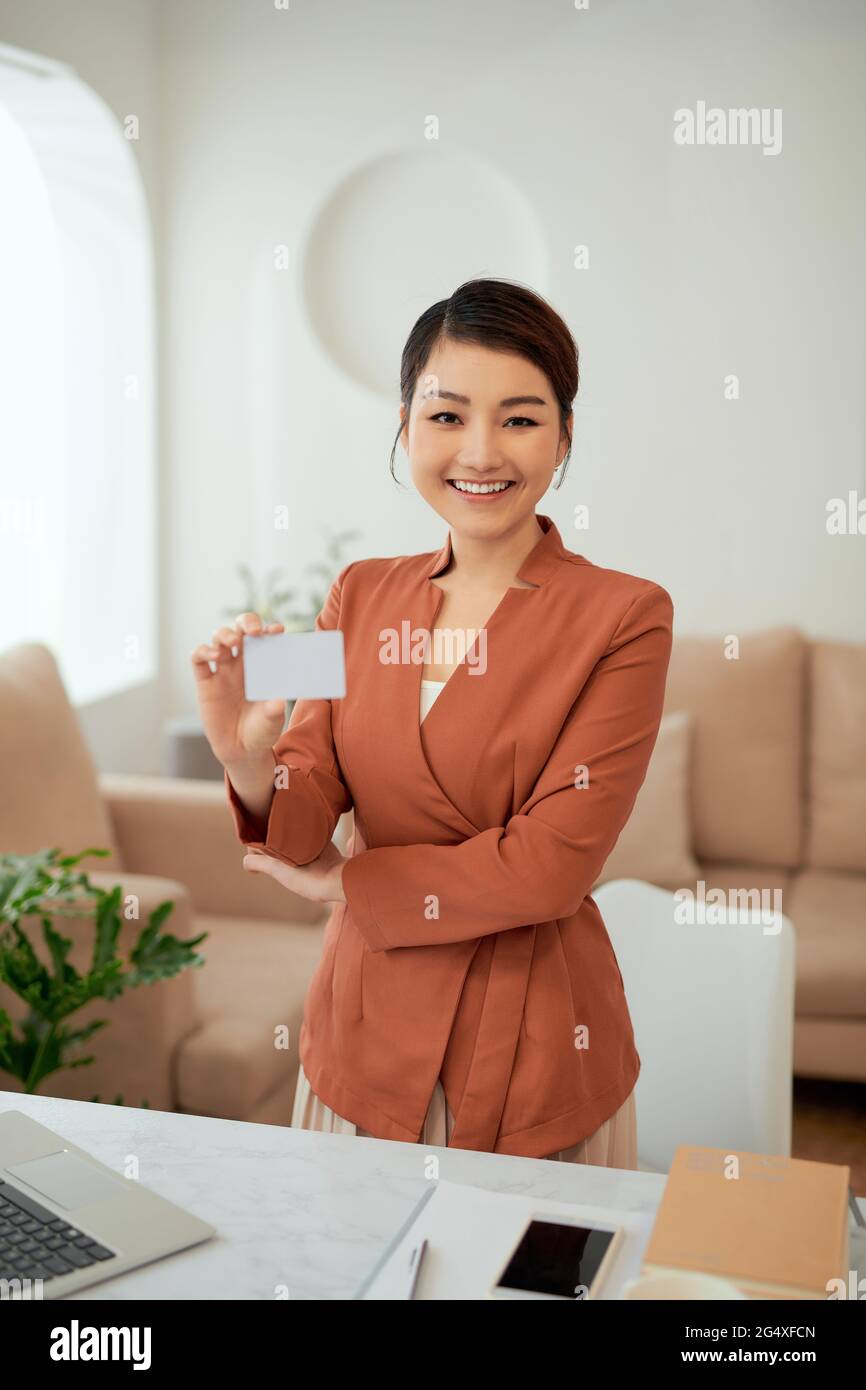 Portrait d'une femme d'affaires tenant une carte de visite dans une salle de bureau Banque D'Images