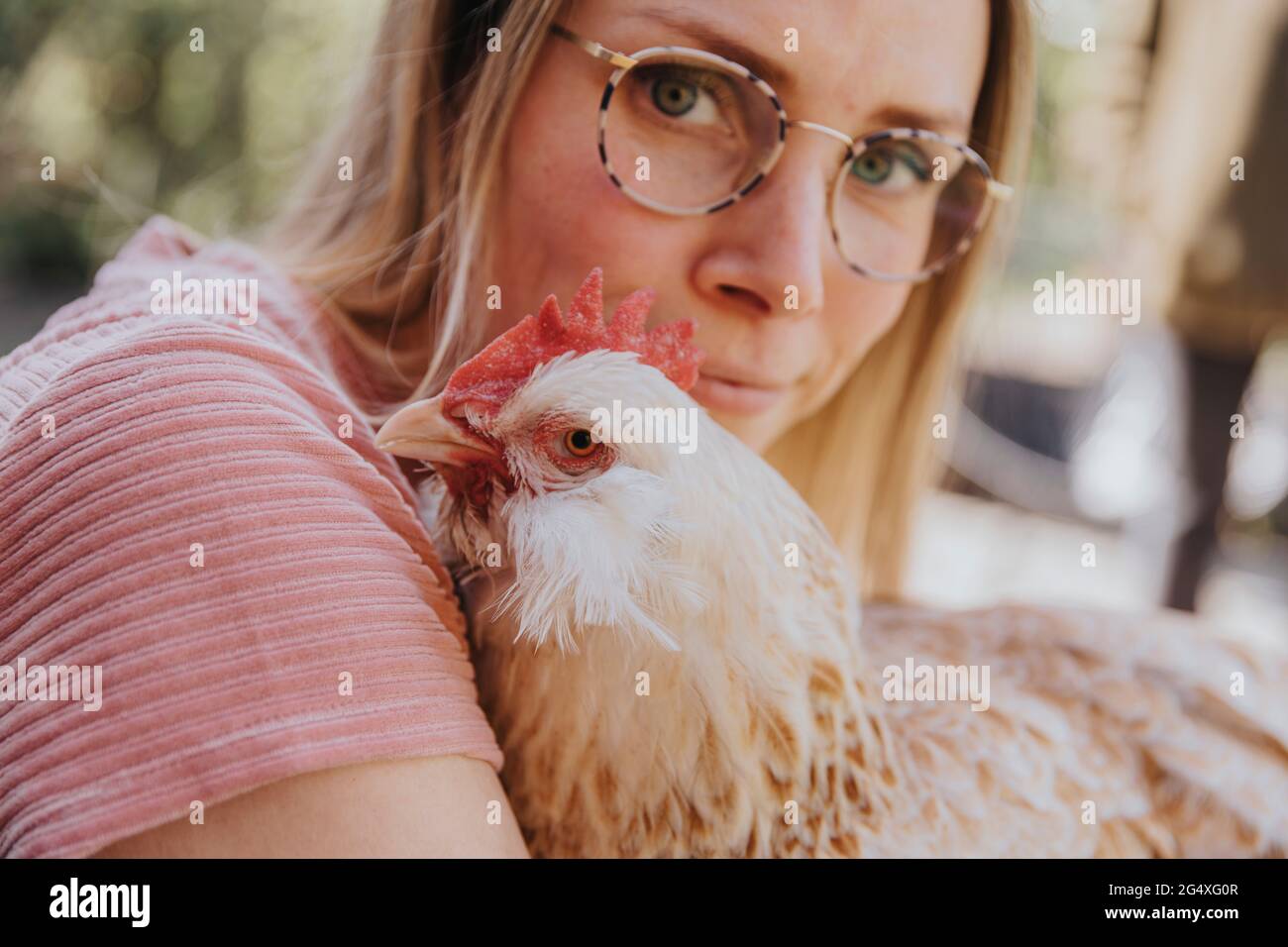 Femme avec des lunettes de vue regardant tout en embrassant le poulet Banque D'Images