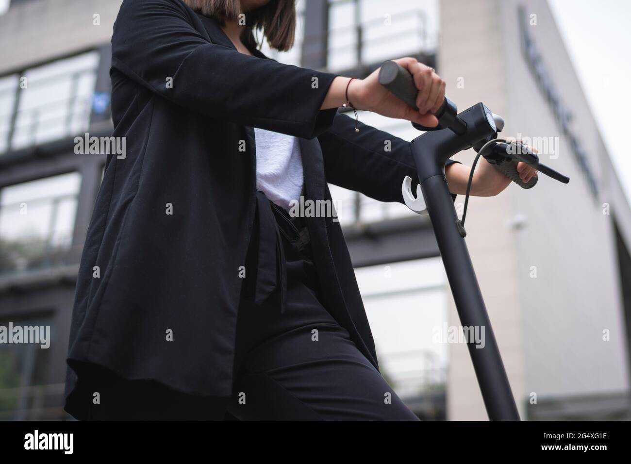 Femme d'affaires debout avec un scooter électrique Banque D'Images