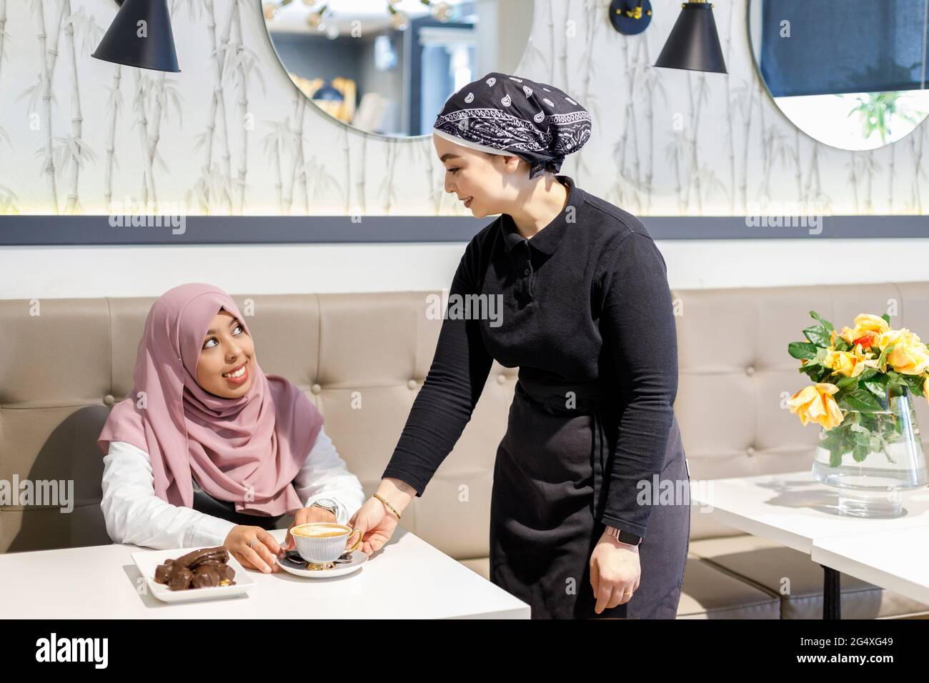 Un barista souriant sert du café à une cliente au café Banque D'Images